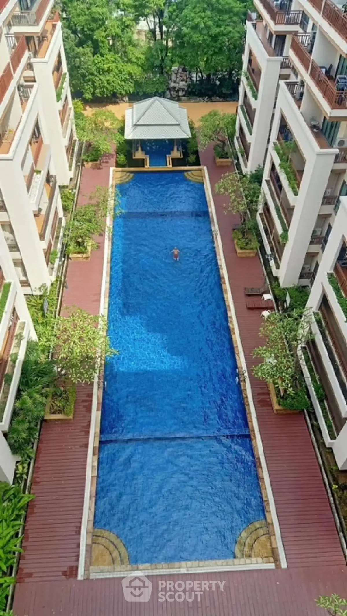 Luxurious apartment complex with a stunning central swimming pool and lush greenery.