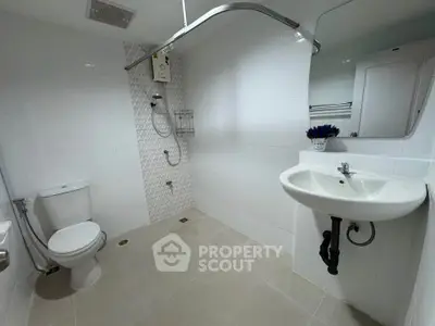 Modern bathroom with white tiles, shower, and sleek fixtures in a contemporary home.