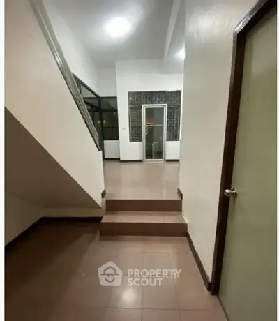 Spacious interior hallway with stairs and tiled flooring in modern home.