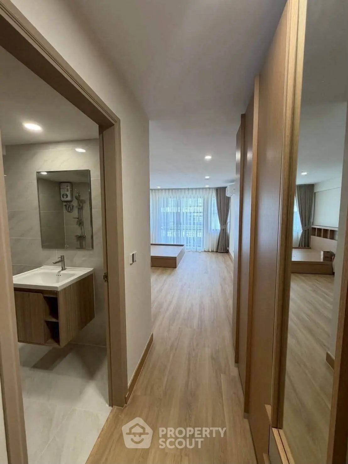 Spacious modern apartment with open layout and wooden flooring, featuring a sleek bathroom and large windows.