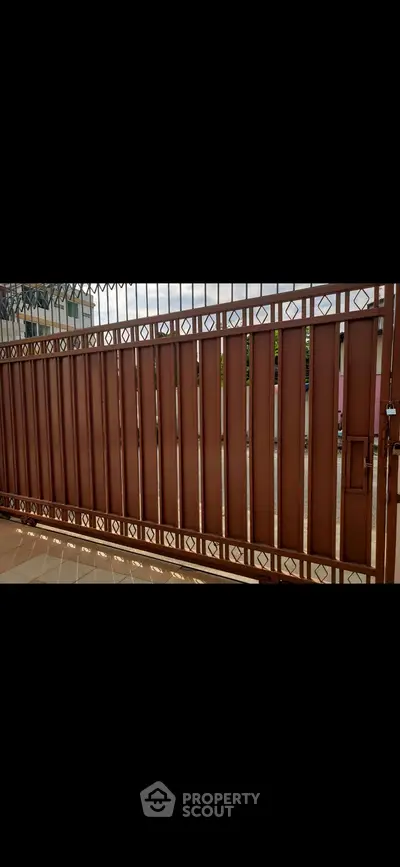 Elegant metal gate with intricate design in a residential setting.
