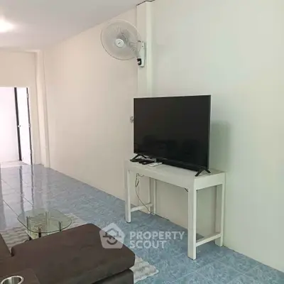 Spacious living room with modern TV setup and sleek tiled flooring.