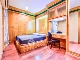 Cozy bedroom with wooden paneling and built-in desk, perfect for relaxation and work.