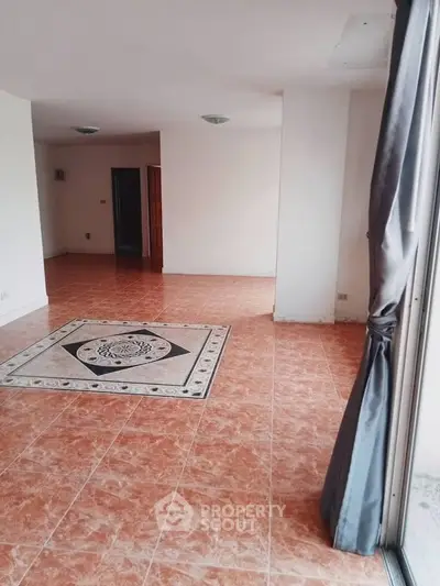 Spacious living room with tiled floor and large window, perfect for natural light.