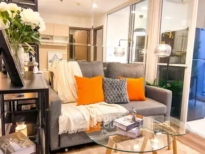 Modern living room with stylish decor and vibrant orange cushions.
