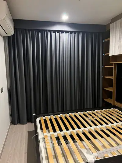 Modern bedroom with sleek design and wooden bed frame, featuring dark curtains and built-in storage.