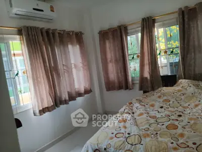 Cozy bedroom with air conditioning and large windows for natural light.