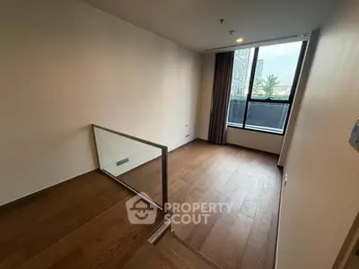 Spacious room with wooden flooring and large window offering natural light, ideal for versatile use.