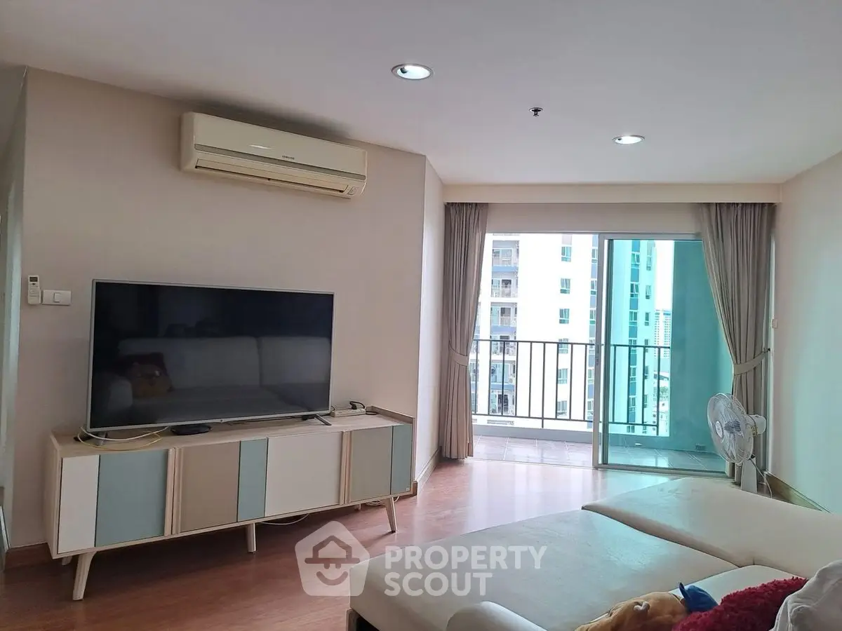Modern living room with balcony view, featuring sleek furniture and ample natural light.