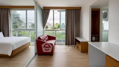 Spacious bedroom with large windows and modern furnishings, featuring a red sofa and wooden accents.
