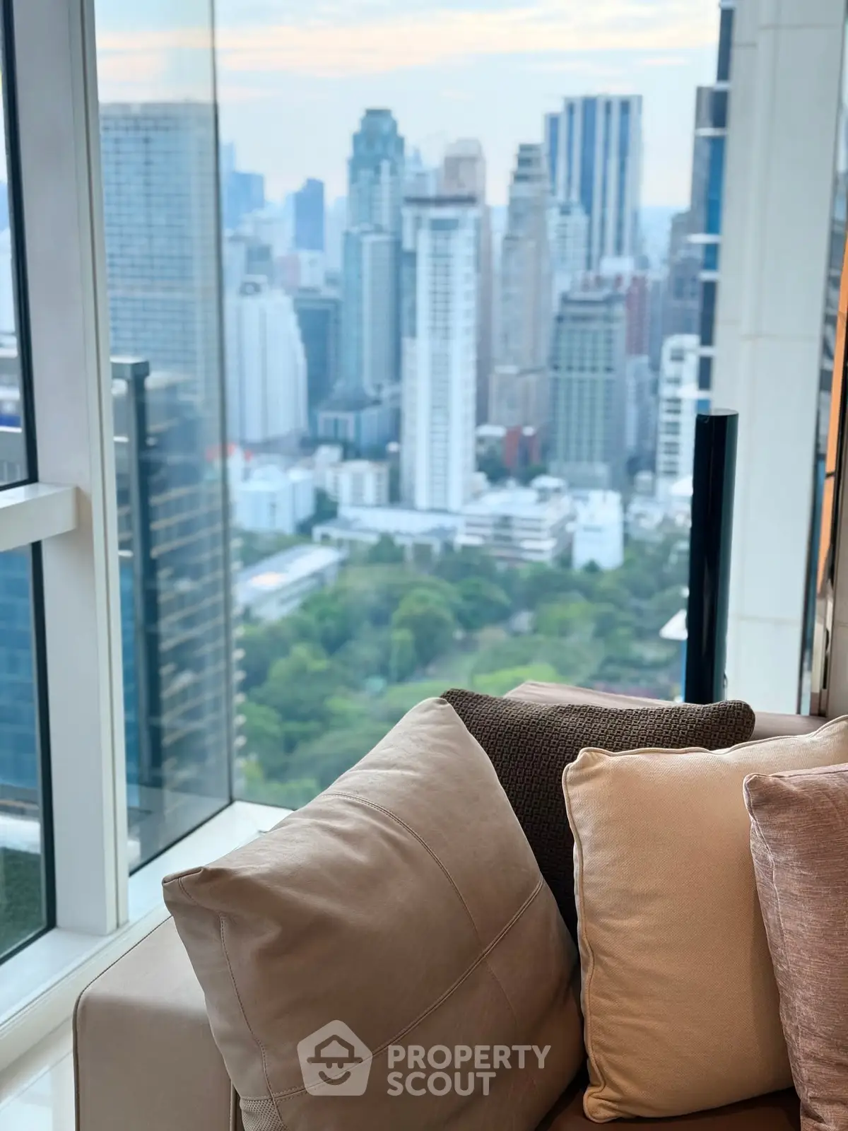 Luxurious high-rise apartment with stunning city skyline view and plush seating.
