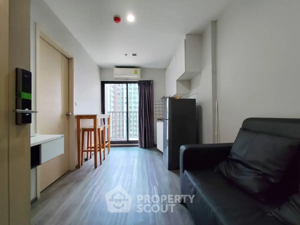 Modern apartment interior with sleek kitchen and cozy living area, featuring a balcony with city view.