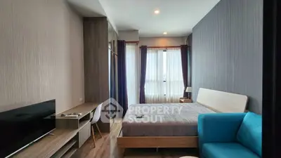 Modern bedroom with stylish decor, featuring a cozy bed, sleek desk, and ample natural light from large windows.