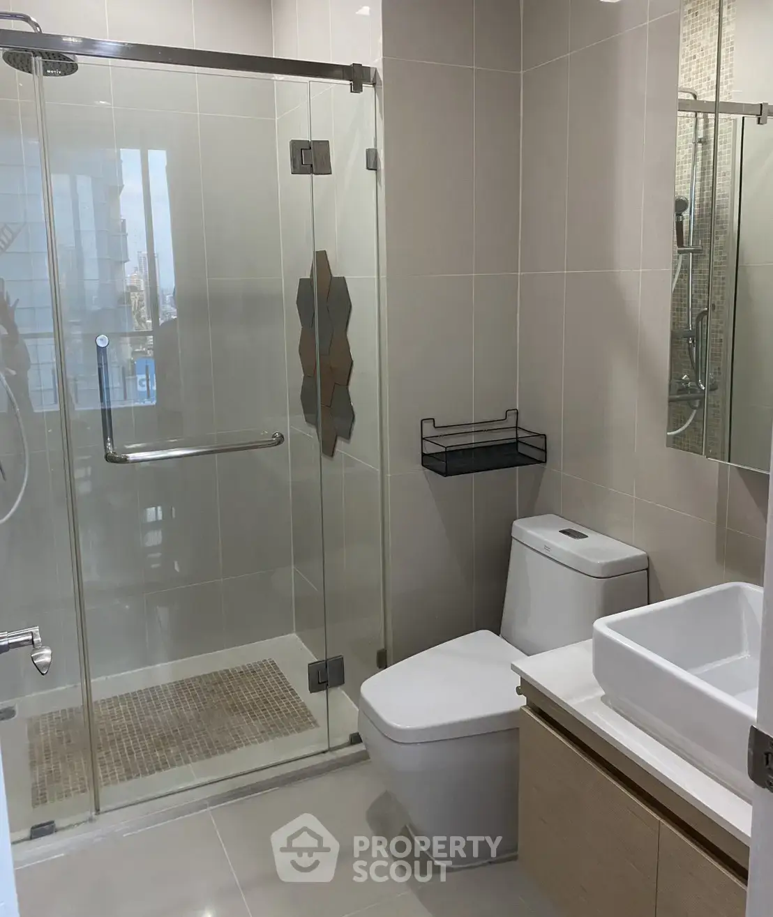 Modern bathroom with glass shower, sleek fixtures, and neutral tiles.