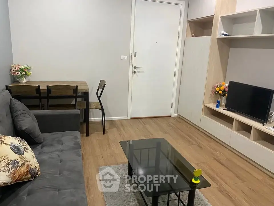 Cozy living room with modern decor, featuring a comfortable sofa, glass coffee table, and wall-mounted TV.