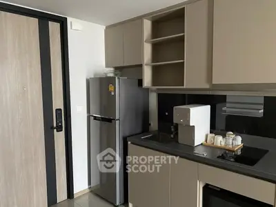 Modern kitchen with sleek cabinetry, compact fridge, and built-in appliances in a stylish apartment.