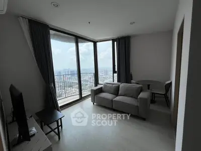Modern living room with large windows offering stunning city views, featuring a cozy sofa and dining area.