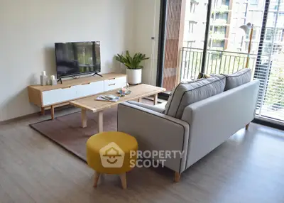 Modern living room with stylish furniture and large windows overlooking a balcony.