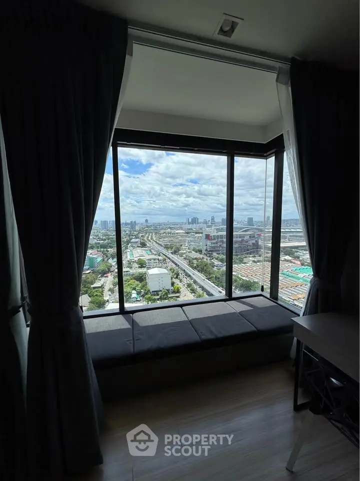 Stunning cityscape view from a modern high-rise apartment window, featuring a cozy seating area.