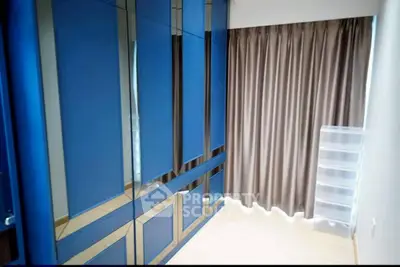 Spacious bedroom with modern blue wardrobes and elegant curtains.