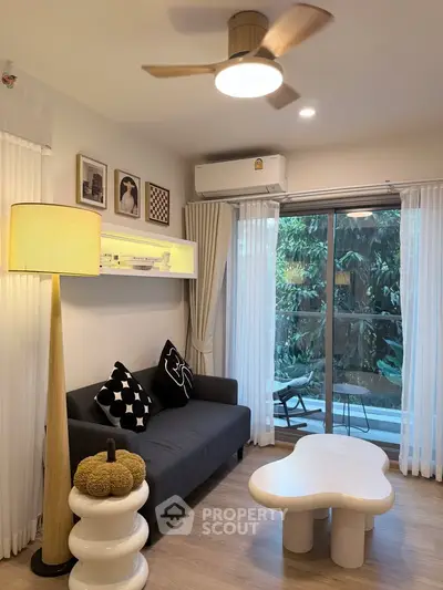 Chic modern living room with stylish decor and large window overlooking lush greenery.