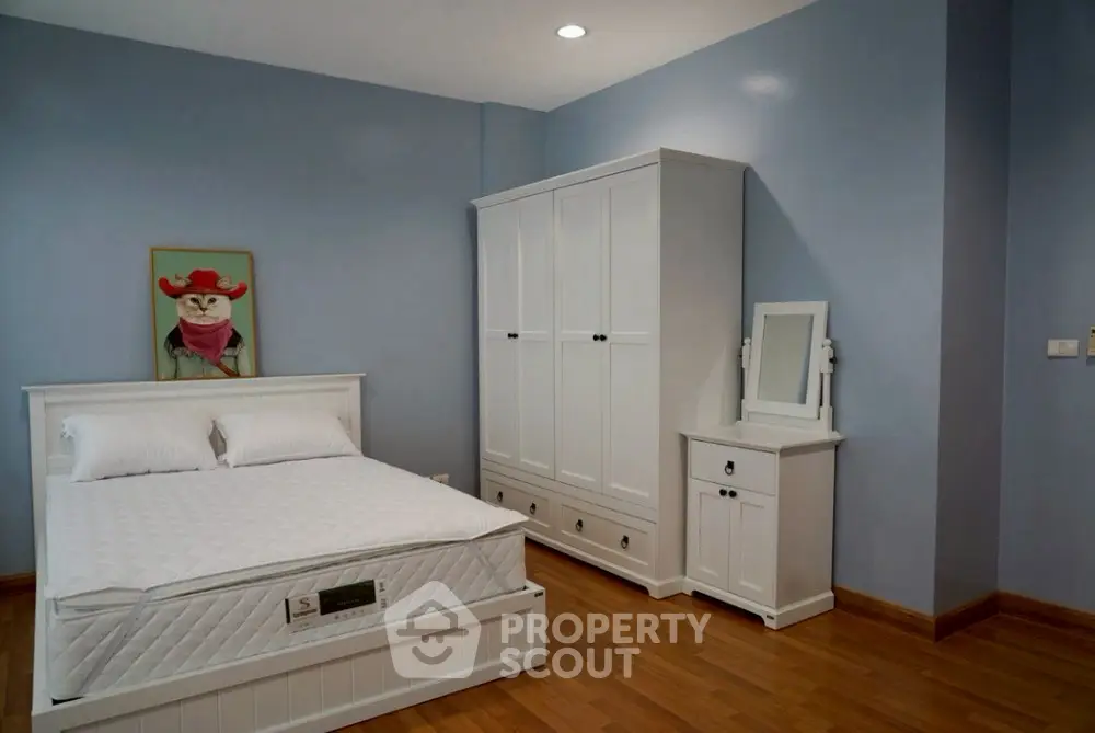 Charming bedroom with white furniture and wooden flooring, perfect for cozy living.