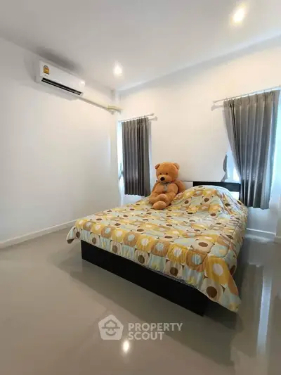 Cozy bedroom with modern decor and plush teddy bear on bed, featuring air conditioning and natural light.