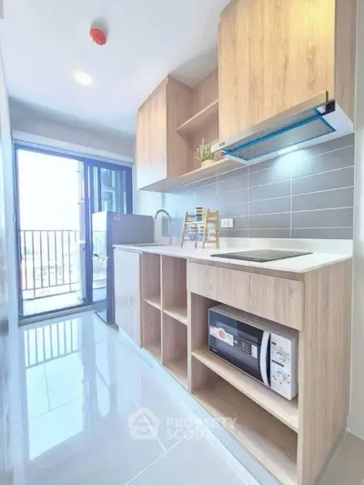 Modern kitchen with sleek cabinetry and appliances, featuring a bright and airy design with balcony access.