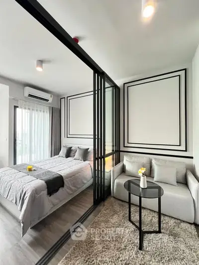 Modern bedroom with glass partition and cozy seating area in stylish apartment.