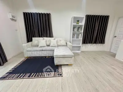 Modern living room with stylish sofa and bookshelf, featuring elegant curtains and wooden flooring.