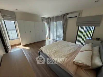 Spacious bedroom with modern decor and balcony access, featuring ample natural light and stylish furnishings.