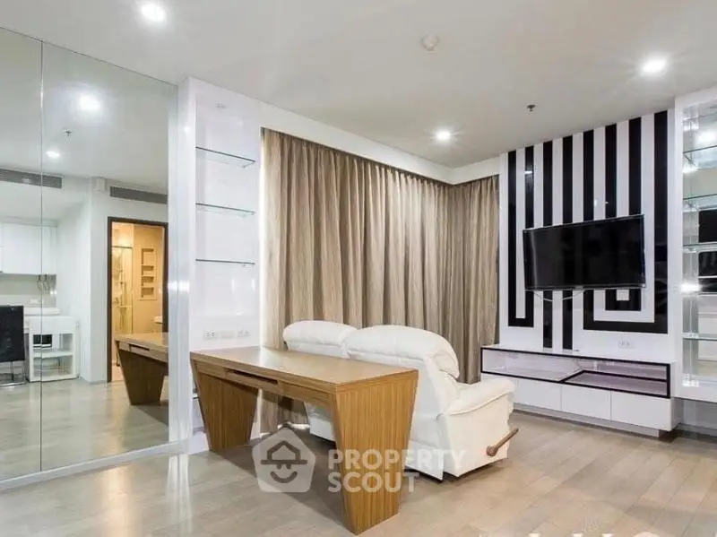 Modern living room with stylish decor, featuring a wall-mounted TV and elegant furniture.