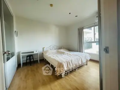 Bright and airy bedroom with wooden flooring and large window in modern apartment.