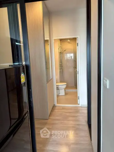 Modern apartment hallway leading to a compact bathroom with sleek fixtures.