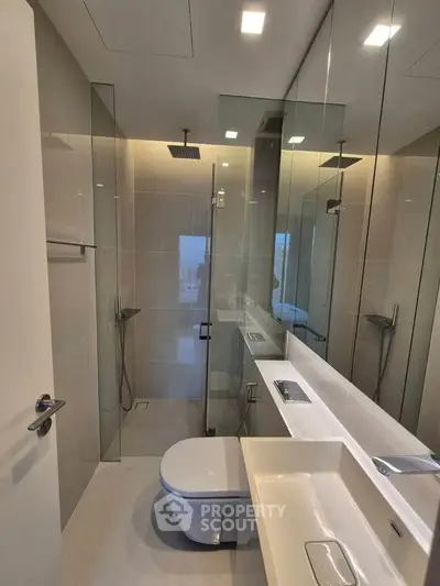 Modern bathroom with sleek fixtures and glass shower enclosure in luxury apartment.