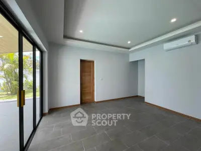 Spacious modern living room with large sliding glass doors and sleek tile flooring.