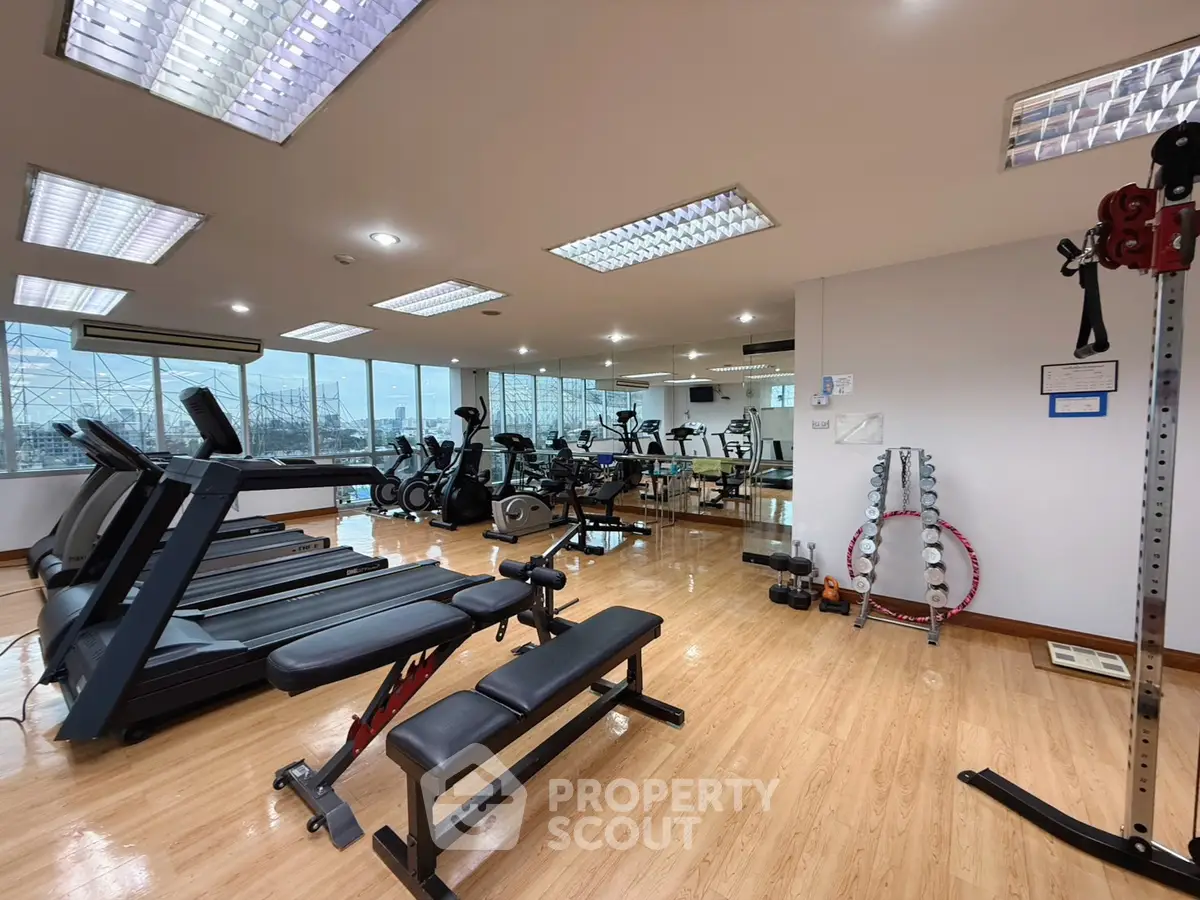 Spacious gym with modern equipment and large windows offering natural light.