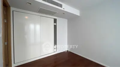 Spacious empty room with wooden flooring and built-in wardrobe