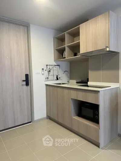 Modern compact kitchen with wooden cabinets and built-in appliances in a stylish apartment.
