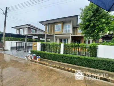 Modern two-story house with lush greenery and secure gated entrance in a suburban neighborhood.