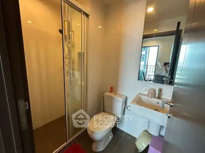 Modern bathroom with glass shower, sleek fixtures, and large mirror in a contemporary apartment.