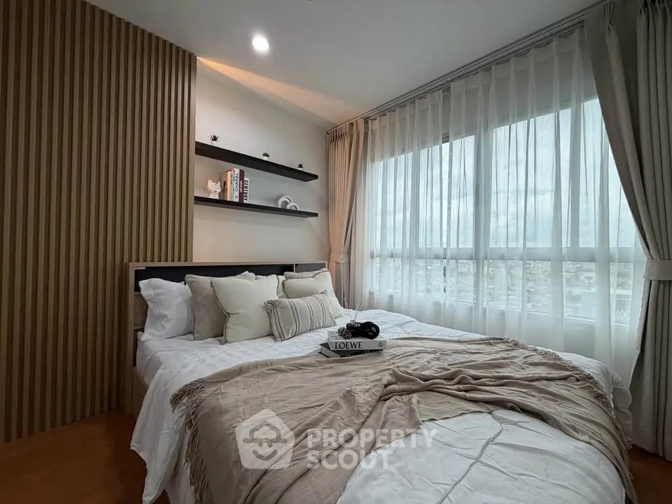 Cozy bedroom with elegant decor and large window offering natural light and city views.