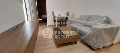 Modern living room with wooden flooring and furniture, featuring a sofa and dining table.