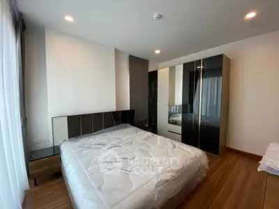 Modern bedroom with sleek design and ample natural light, featuring a stylish wardrobe and wooden flooring.