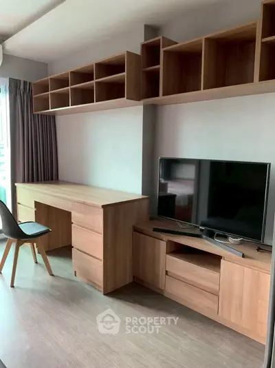 Modern study room with wooden desk, shelves, and TV unit in a stylish apartment.