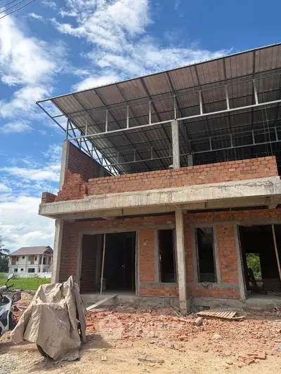 Under-construction brick building with open framework against a clear blue sky, showcasing potential for development.