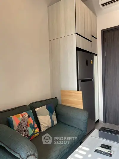 Cozy modern living room with stylish sofa and sleek kitchen appliances.