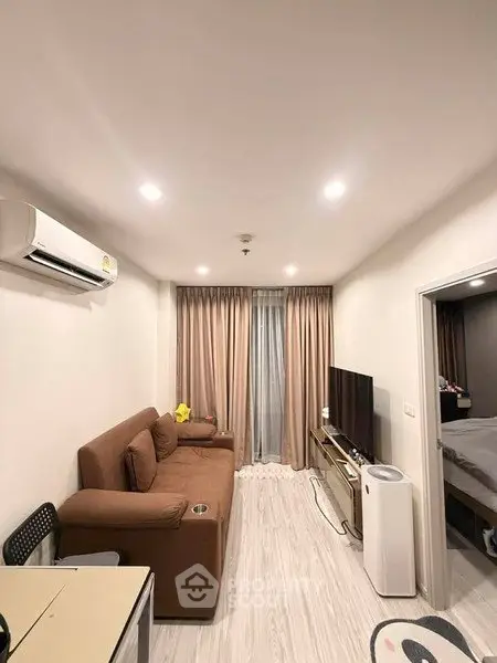 Modern living room with brown sofa, air conditioning, and flat-screen TV in cozy apartment.