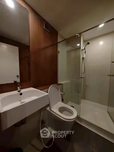 Modern bathroom with sleek fixtures and glass shower enclosure in a contemporary apartment.