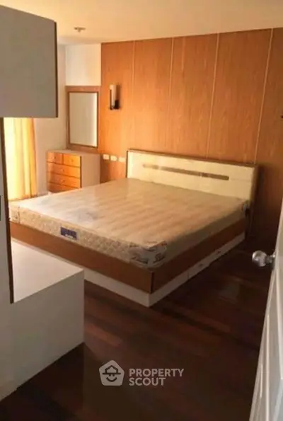 Spacious bedroom with wooden flooring and modern furniture